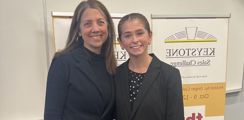 Two women stand side by side smiling.